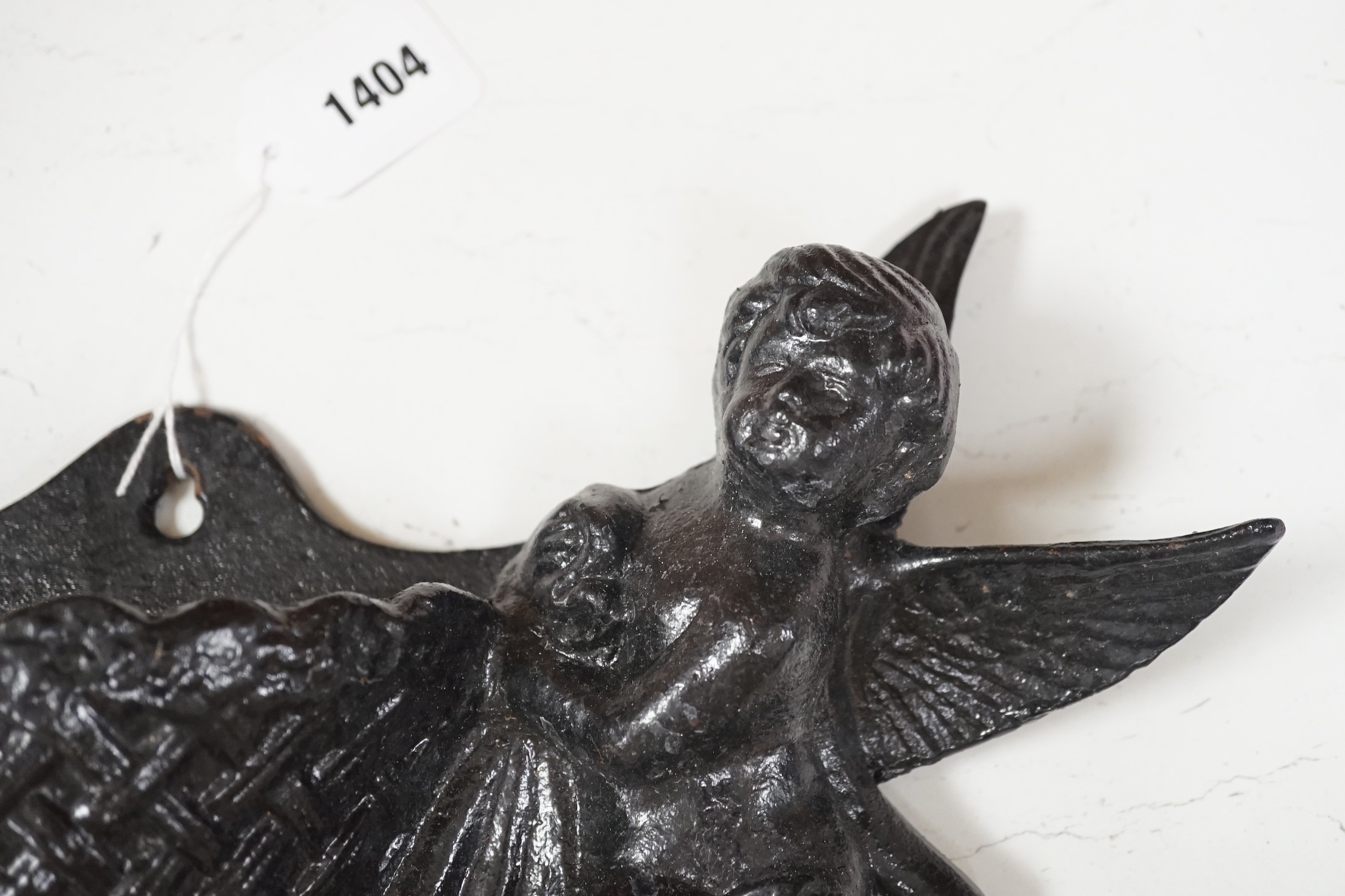 A black painted cast iron cherub flower wall bracket. 40cm wide